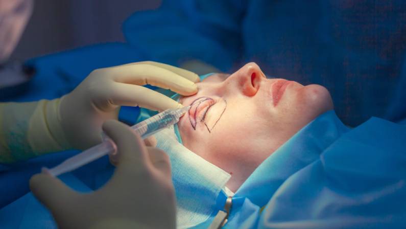 Surgeon inserts an injection into the upper eyelid of the patient before performing the eyelid lift operation.