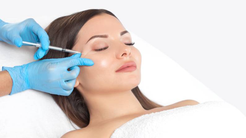 Cosmetologist makes rejuvenating anti wrinkle injections on the face of a beautiful woman.