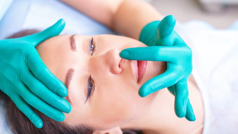 Doctor checking woman's face, nose before plastic surgery.