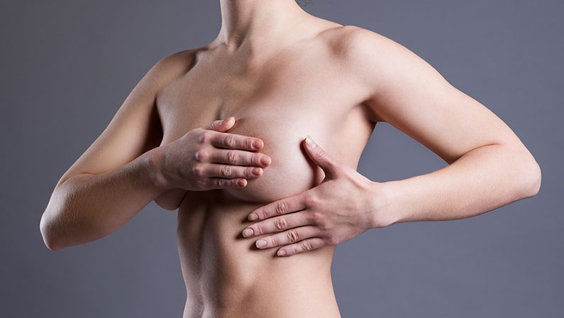 Woman examining her chest before breast reconstruction surgery, evaluating size and contour restoration options.
