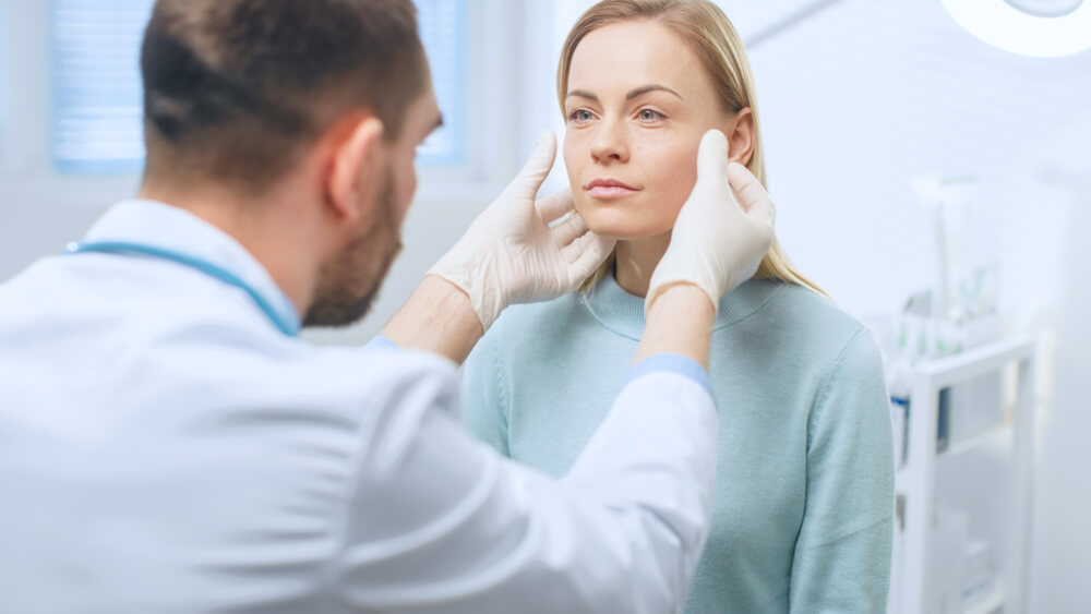 Plastic surgeon assessing a patient’s facial structure before Rhytidectomy to plan for natural, youthful results.