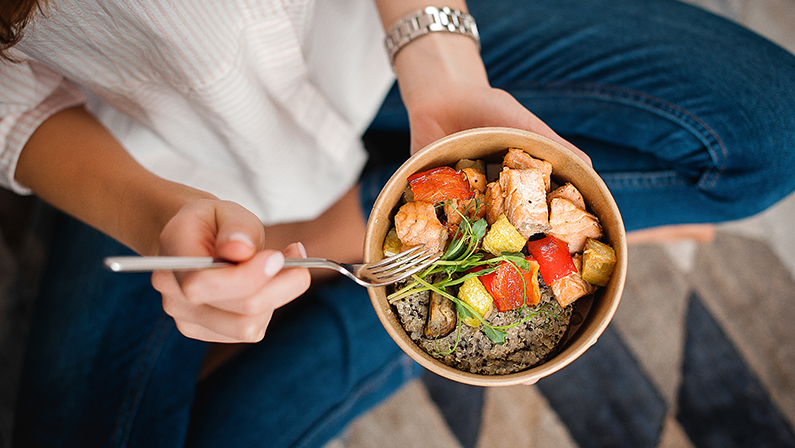 Person eating a healthy bowl of food to support healing and improve overall Recovery Time for Liposuction results.
