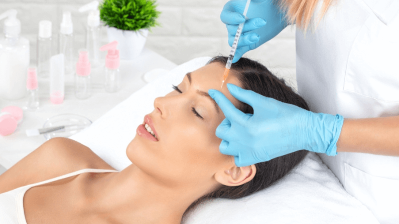Cosmetologist makes rejuvenating anti wrinkle injections on the face of a beautiful woman.