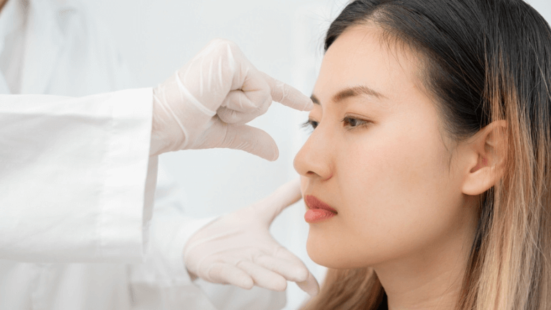 Surgeon touching woman face before liquid rhinoplasty procedure.