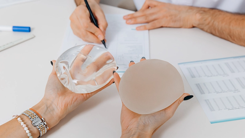 A woman chooses plastic breast implants at a doctor's consultation.