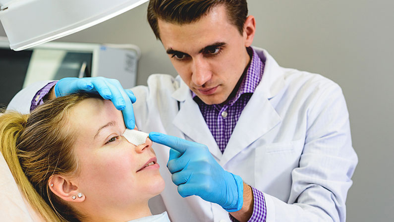 Male doctor preparing a mold of the curve of the nose the patient is female, to follow the alignment procedure of the nose. Rena Therme Hartman for plastic surgery.