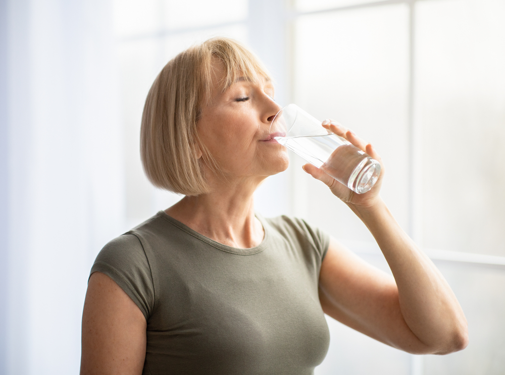 Fit senior woman drinking clear water
