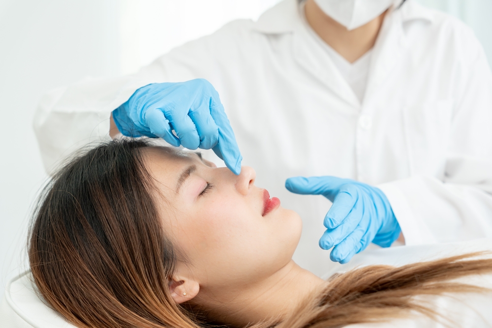 doctor examines patient nose before rhinoplasty