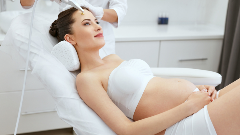 Pregnant woman relaxing in a clinic chair receiving gentle skincare treatment, raising concern about botox while pregnant.