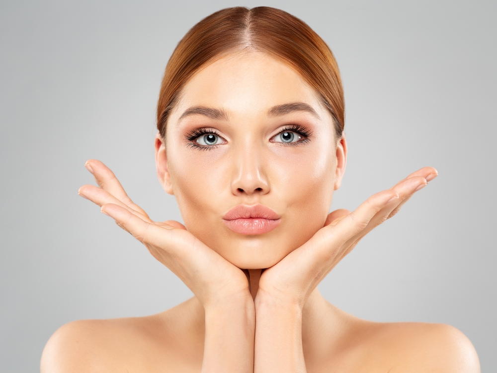 A woman shows off her smooth, youthful skin after a dermal filler treatment