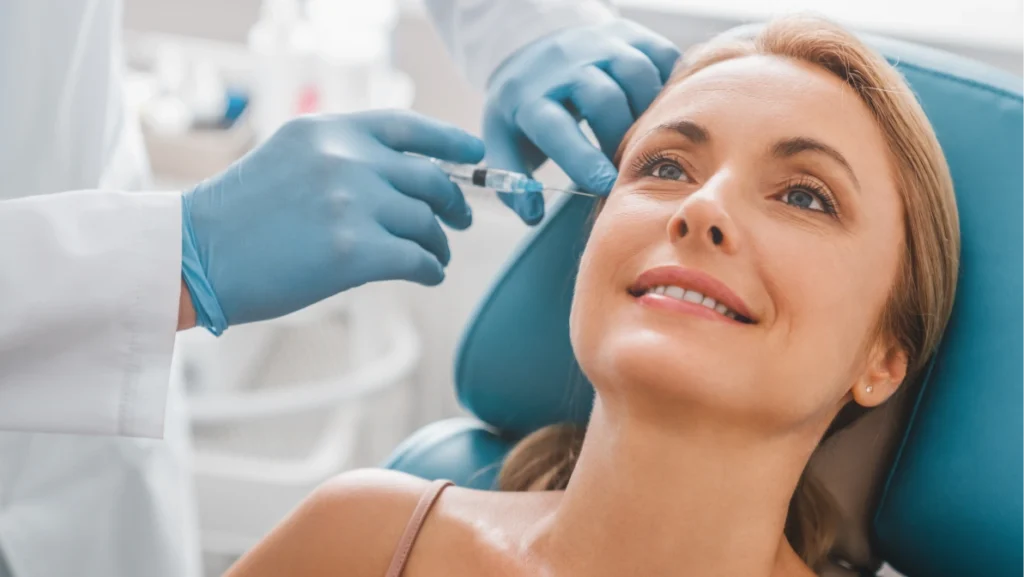 Woman receiving injectable procedure from surgeon as part of mini facelift to tighten and rejuvenate facial skin.