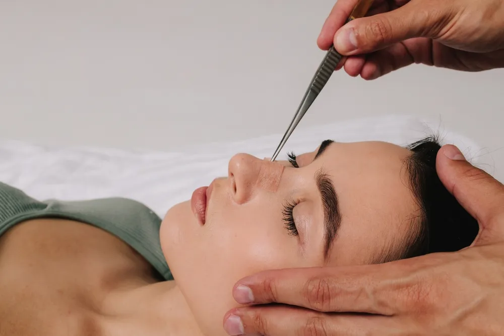 Patient lying down during rhinoplasty check-up, highlighting careful treatment to reduce rhinoplasty scarring.