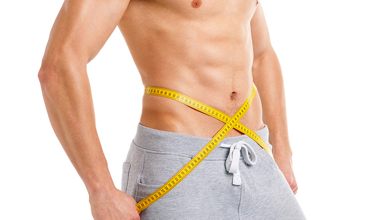 Fit guy with BBL measuring slim waist using yellow tape, highlighting toned results after cosmetic body contouring.