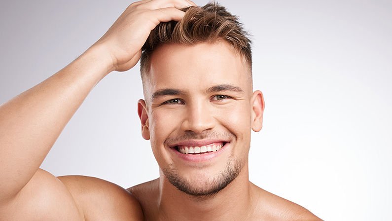 Smiling man touching his hair after aesthetic treatment, representing confidence and results from man gets BBL.