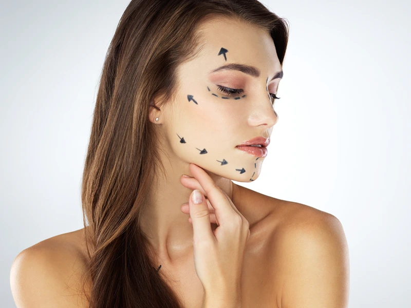 Woman, face and arrows in studio for plastic surgery, chin augmentation and cosmetic procedure. Female person, skincare and rhinoplasty on white background for beauty, liposuction and transformation