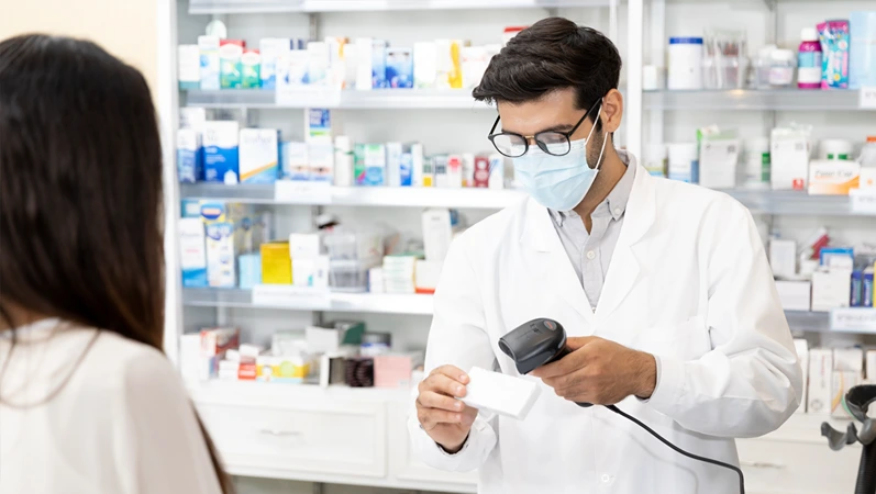 Middle eastern male pharmacist scanning barcode of medicine drug to customers in modern pharmacy