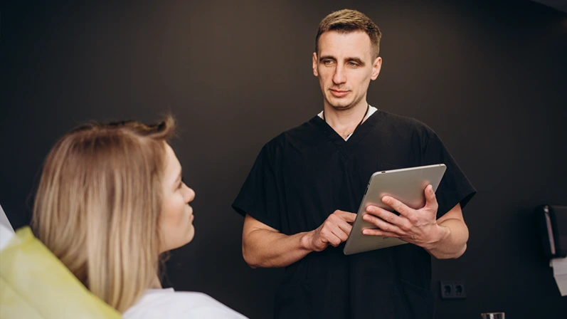Plastic, Cosmetic Surgeon Consults Woman about Facial Lift Surgery, He Draws Arrows on Digital Tablet Computer Screen, Showing Types of Facelift and Nose Correcting Procedures Available for Her.
